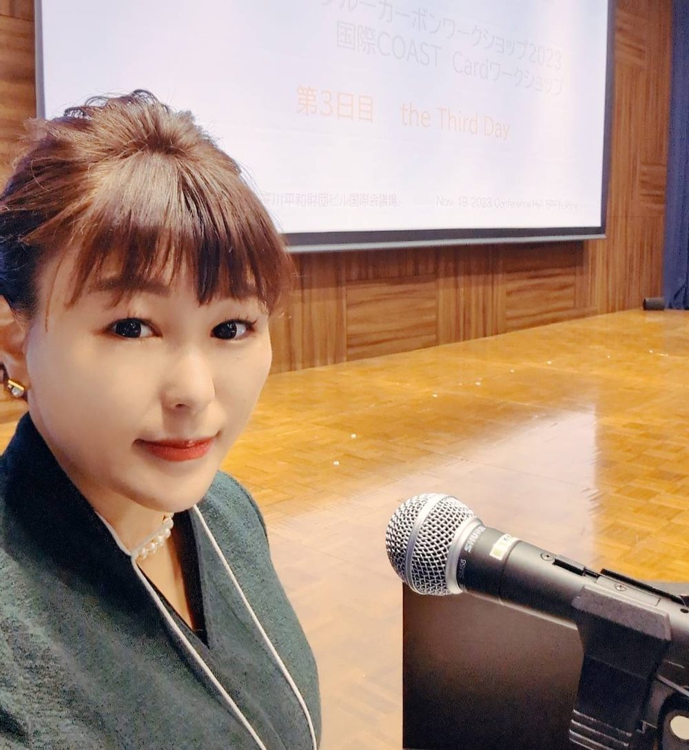 国際会議の会場で司会席に立つ佐伯桃子