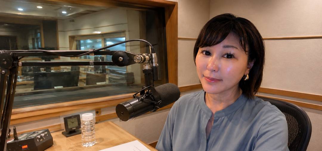 ラジオの収録ブースでマイクの前に座る佐伯桃子