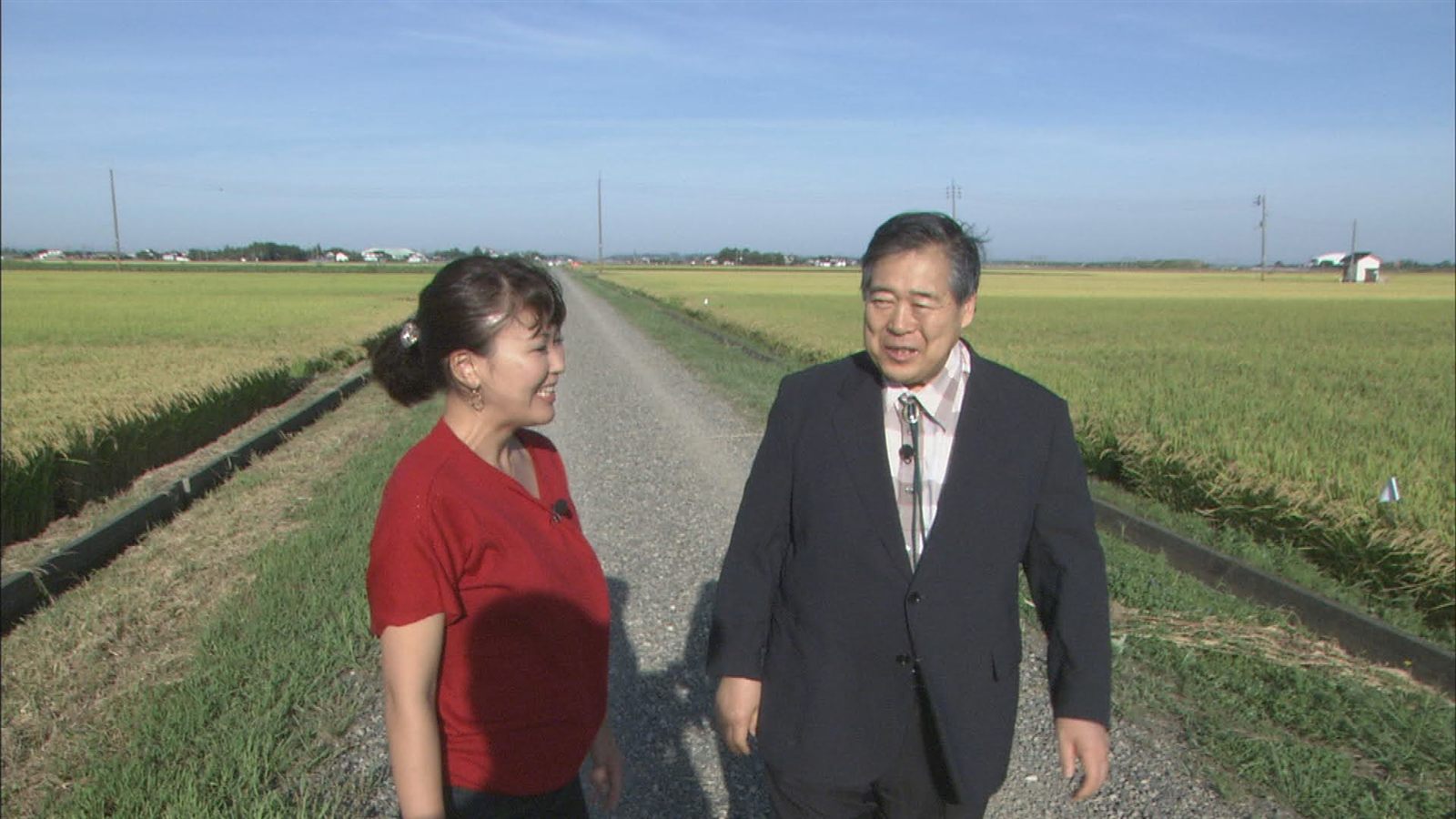 稲の実る畦道で取材する佐伯桃子